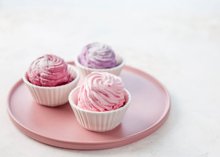 Three types of meringue on a pink plate. The taste of strawberries, lavender and blackcurrant