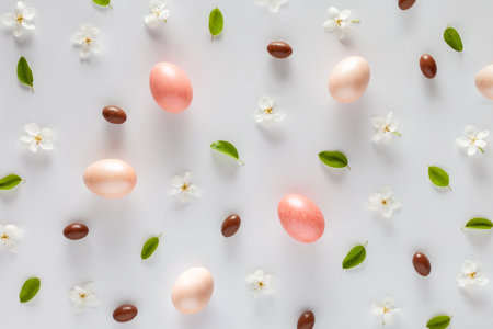 Easter background. Pattern made of eggs, flowers and candies on a white background. flat lay.の写真素材