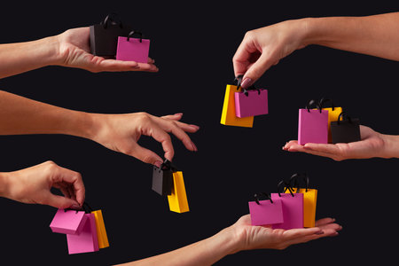 Black friday sale concept. Female hands holding shopping bags on a black background.の写真素材