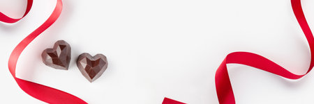 Chocolate hearts and red ribbon on a white background. Valentine's Day banner. Copyの写真素材