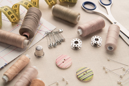 Sewing supplies and accessories for needlework. Fabric, spools of thread, scissors and thimbles on a table.の写真素材
