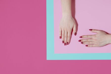 Manicure in a trendy dark red color on a colored background. Flat lay style.の写真素材