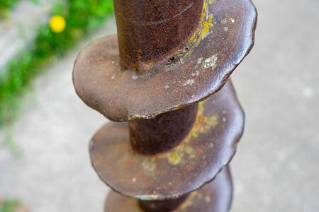 Part of an old rusty drill drilled into the ground . Metal rusty drillの写真素材