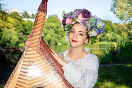 Young Ukrainian woman in a national white shirt hugs a bandura.