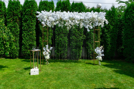 White wedding arch on a background of evergreen thuja. Summer wedding ceremony in the park.の写真素材