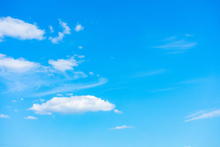 Several small white clouds on a blue sky background.
