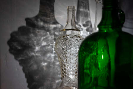 Abstract image of shaped glass bottles with a bright reflection on the wall.の写真素材
