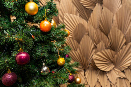 A beautifully adorned Christmas tree stands with vibrant ornaments against a textured brown backdrop. The festive spirit is palpable as decorations reflect holiday cheer.の写真素材
