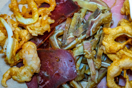 A vibrant platter features a selection of fried meats, including crispy pork, beef, and sauteed...