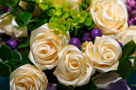 A beautiful bouquet cream features-colored artificial roses surrounded by green foliage and purple accents. This decorative arrangement adds charm to any space.の写真素材