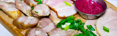 A beautifully arranged selection of cured meats sits on a wooden board, alongside a vibrant dipping sauce and garnished with fresh green onions, evoking a rustic dining experience.の写真素材