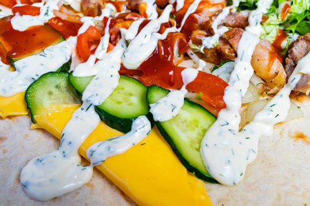 A delicious wrap is filled with tender chicken, fresh cucumber, tomatoes, and leafy greens, all...