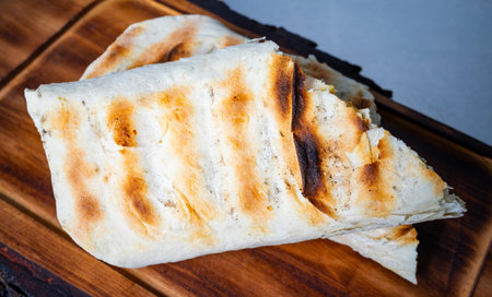 Grilled flatbread rests on a wooden board, showcasing a crispy exterior and inviting aroma. Perfect...