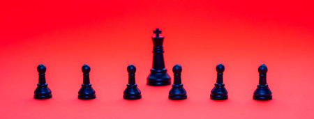 Black chess pieces including a king and pawns are positioned on a vivid red backdrop. The...