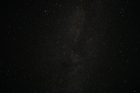 A breathtaking view of countless stars scattered across a clear night sky, illuminating the darkness above a serene landscape. The tranquility of the scene invites reflection and awe.の写真素材