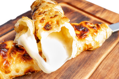 Freshly baked pastry is oozing with melted cheese, served on a wooden cutting board. The crispy...