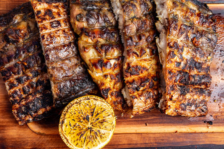 Deliciously grilled fish fillets are sliced and presented on a wooden board, accompanied by a...