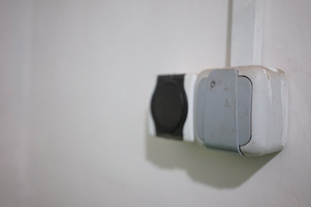Two electrical outlets are mounted on the wall, one is showing wear while the other is clean. The setup allows for appliance connections in a quiet room, emphasizing functionality.の写真素材