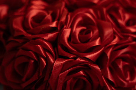 Intricately arranged red silk roses create an elegant display, showing their rich color and shine. Perfect for decorative purposes or as a loving gift for special occasions.の写真素材