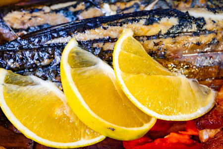 Succulent grilled fish fillets are presented on a plate, garnished with fresh lemon slices. Brightly colored vegetables accompany, enhancing the meal's visual appeal and flavor.の写真素材