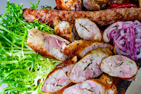 A platter of grilled sausages and meats showcases layers of flavor, accompanied by vibrant greens and pickled onions. Perfect for a hearty meal or gathering.の写真素材