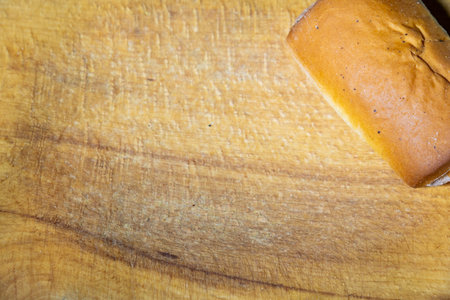 A golden-brown loaf of bread is placed on a rustic wooden cutting board, showing its soft texture...