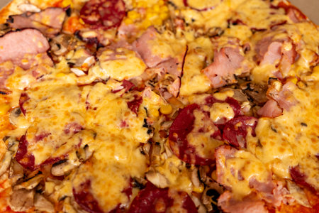 Golden melted cheese covers a thick crust, topped with savory meats and sliced mushrooms. This delicious meal is perfect for sharing during a casual gathering or celebration.の写真素材