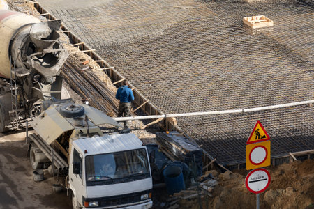 Construction site with concrete mixer and worker at building location