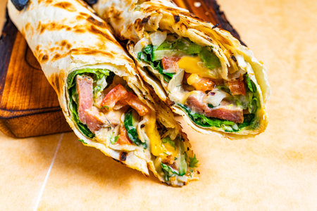 A fresh wrap is filled with crisp lettuce, tomatoes, and melted cheese. It is beautifully presented...