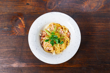 A plate of creamy seafood pasta garnished with herbs sits on a rustic wooden table. The dish showcases a blend of flavors and textures, perfect for a cozy dining experience.の写真素材
