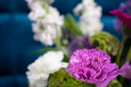 A diverse bouquet featuring pink, white, and green flowers is artfully arranged against a blue background. The floral display adds a lively touch to the interior decor.の写真素材
