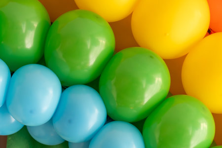 Bright green, yellow, and blue balloons are arranged together, adding a vibrant touch to the decor at a joyful celebration. The colors evoke a sense of fun and excitement.の写真素材