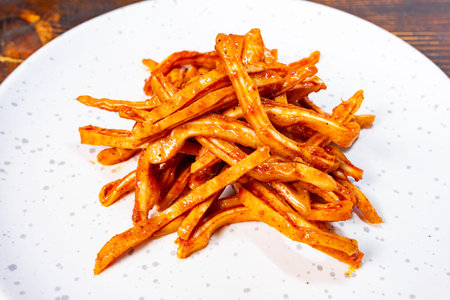 Deliciously spicy pickled pig ears served on a white plate in a rustic setting