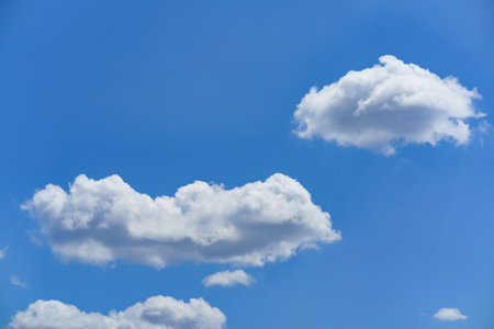 Soft, fluffy clouds are drifting across a bright blue sky. The scene captures the tranquility of a...