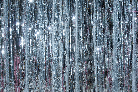 The shimmering silver curtain hangs beautifully, reflecting light in a spectacular display. Its sequins sparkle as they catch the glow from the bright lights, enhancing the festive atmosphere in the event space during the evening.の写真素材