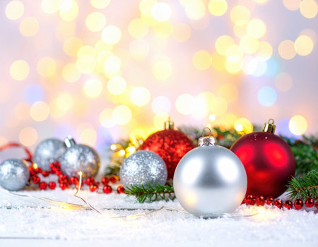 Colorful Christmas ornaments in silver, red, and glitter adorn a snowy surface and twinkling lights enhance the joyful atmosphere.の素材