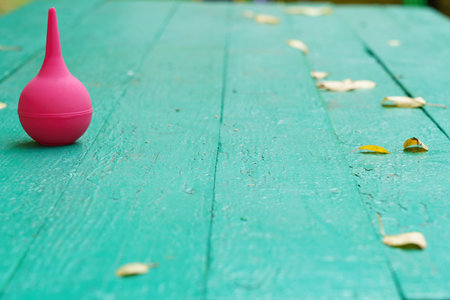 A bright pink bulb sits on a green wooden table scattered with yellow leaves. The scene captures a vibrant autumn atmosphere.の写真素材