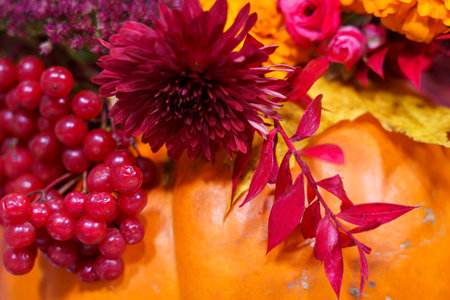 Bright pumpkins are adorned with colorful flowers and fresh berries, showing the beauty of autumn at a local market.の写真素材