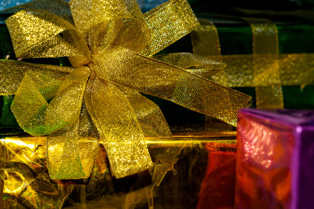 Presents wrapped in shiny paper with colorful bows sit on a table ready for a special event or occasion.の写真素材
