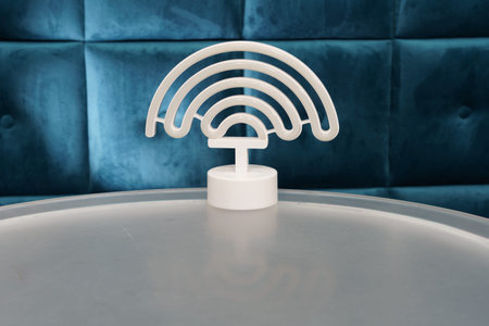 Wifi symbol is placed on a transparent table in a cafe with blue seating. The setting is bright and inviting for customers.の写真素材