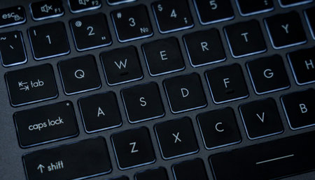 The picture shows a close view of a laptop keyboard in a home office setting during the day. Keys are visible with letters and numbers.の写真素材