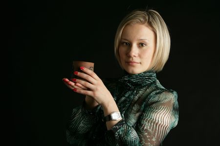 The beautiful young girl-blonde in a green blouse has control over a glassの写真素材