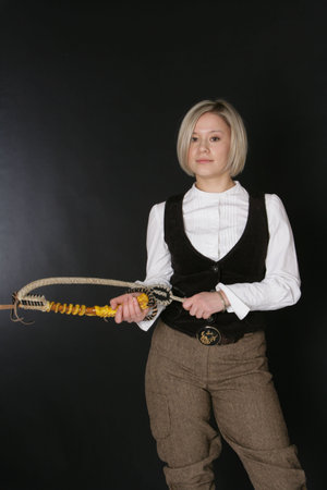 The girl-blonde in a white blouse and a waistcoat with a lash in hands