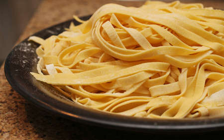 Fresh linguini pasta in a pile on a black plate.の写真素材