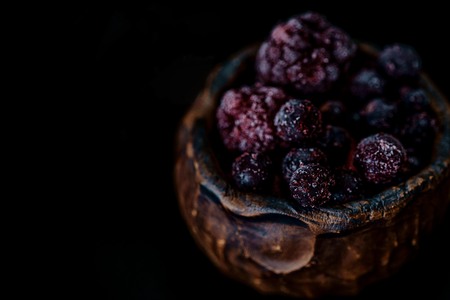 Frozen blueberries in a clay bowl with dark background close upの写真素材