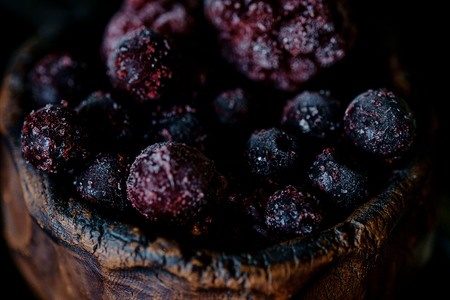 Frozen blueberries in a clay bowl with dark background close upの写真素材