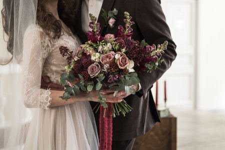 Bride in a wedding dress and groom holding a wedding flowers bouquet.