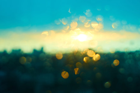 Rain drops texture on window glass with stunning colorful blue yellow and green sunset light...