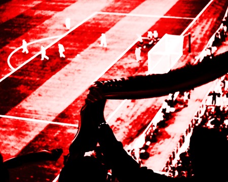 Football fans cheer their soccer team score goal with flags, banners and scarfs at the stadium. Red and black toned view.の写真素材