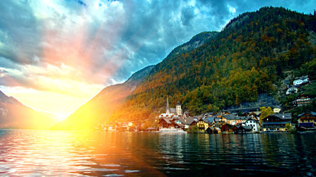 Hallstatt mountain resort village with famous church, traditional alps houses and wooden rural boat...